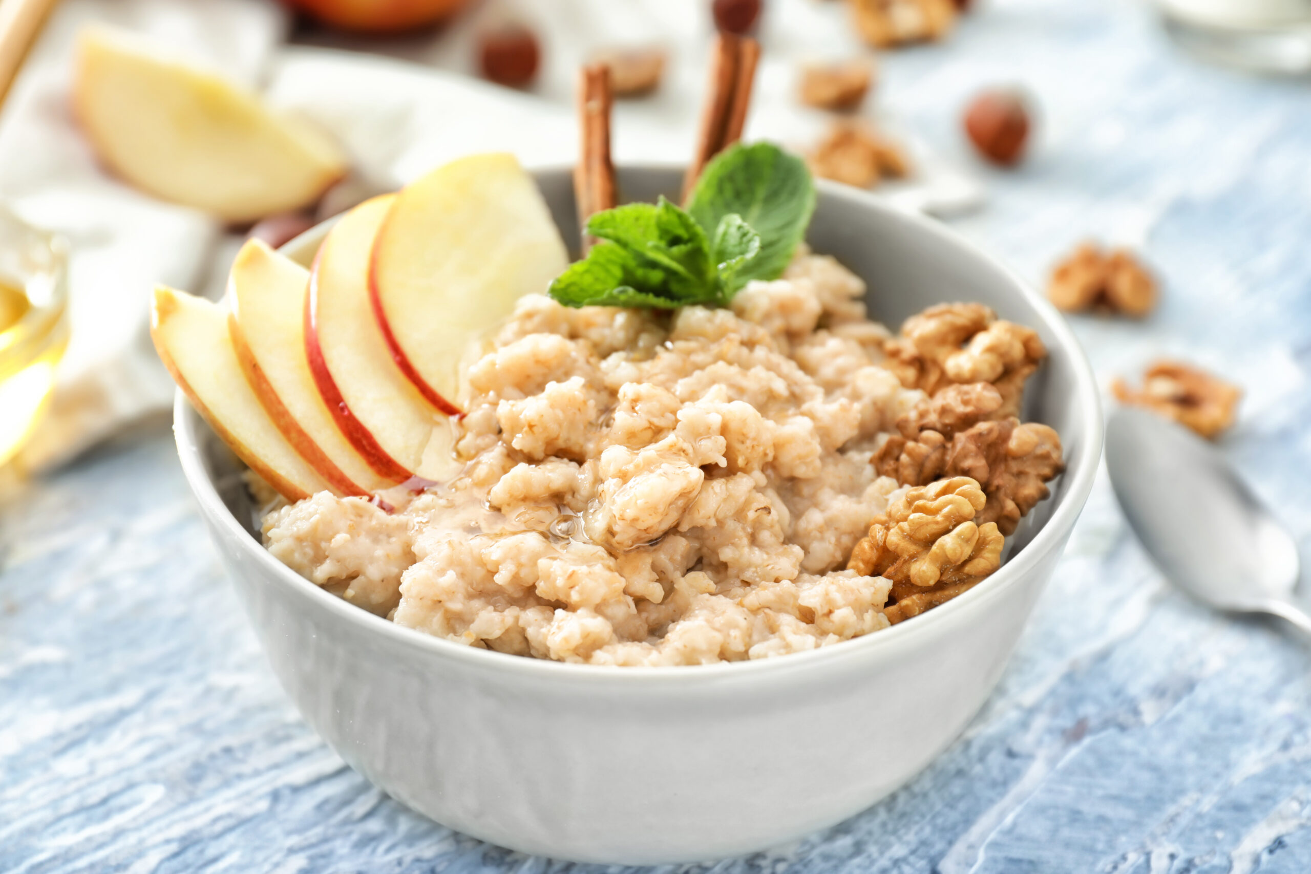 Tasty oatmeal with apple and walnut in bowl on table